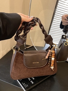 Dark brown minimalist leather shoulder bag with woven handle and vintage bead charm
