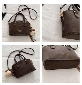 Macro detail of brown leather shell bag showing gold logo and cute plush bear charm