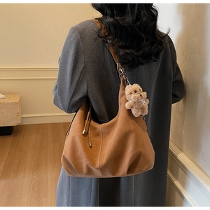 Brown suede hobo tote bag detail with cute teddy bear charm and adjustable shoulder strap