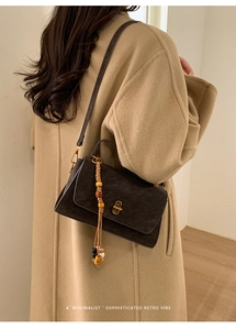 Detail of retro matte brown square bag with gold buckle and colorful beaded charm