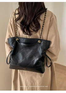 Close-up of black quilted leather tote bag featuring golden chain strap and logo