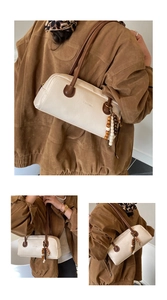 Detail view of cream leather baguette bag with colorful wooden beads and embossed logo