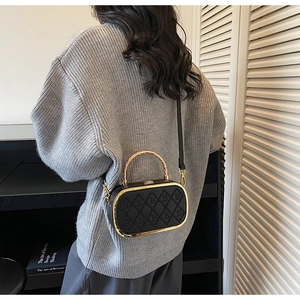 Detail of vintage black quilted handbag with golden bamboo handle and textured B pattern