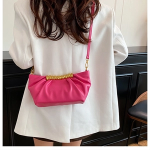 Detail of hot pink pleated leather clutch bag featuring elegant twisted gold metal hardware