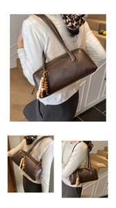 Detail of dark brown baguette bag with unique wooden bead charm and sleek matte finish