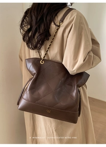 Detailed view of dark brown quilted leather tote bag with gold chain and retro styling