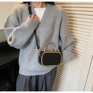 Detail of black quilted leather crossbody bag with gold bamboo handle worn by model