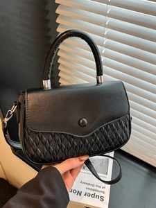 Minimalist black quilted crossbody handbag with round buckle and adjustable strap