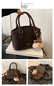 Macro detail of brown faux suede handbag with golden hardware and chic puppy pendant