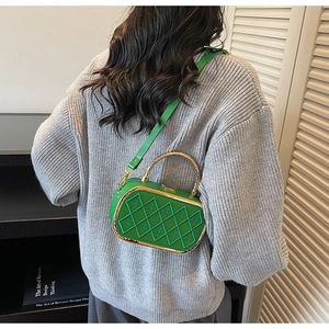 Detail of green quilted leather crossbody bag with gold handle and embossed B patterns