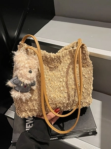 Khaki Woll-Beuteltasche mit Lederriemen und Bärenanhänger auf schwarzen Büchern