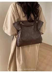 Detail of retro dark brown quilted tote bag with golden metal chain on a model