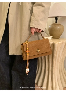 Close-up of retro brown frosted handbag featuring a beaded tassel and metal buckle