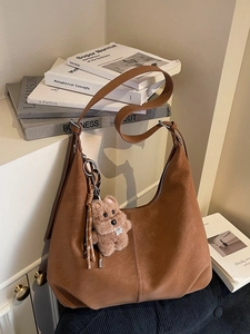 Brown faux suede hobo tote bag with a plush bear charm and adjustable shoulder strap