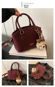 Detail of burgundy suede handbag featuring gold hardware and a cute plush bear charm