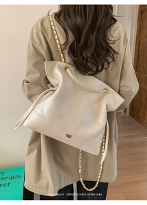 Quilted cream tote bag with gold chain strap shown on model for sizing and style