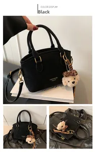 Detail of black vintage handbag with detachable strap and leopard bow bear pendant