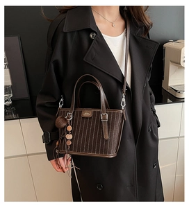 Détail du sac cabas marron à rayures avec breloque à pompon et finitions argentées