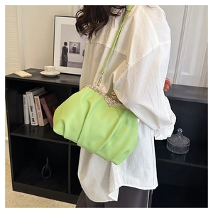 Detail of neon green pleated shell bag featuring a sparkling rhinestone floral clasp