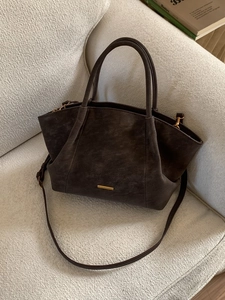 Dark brown suede tote bag with minimalist gold metal trim and adjustable shoulder strap