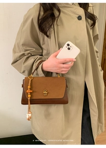 Close-up of retro brown patchwork handbag with gold metal clasp and tassel detail