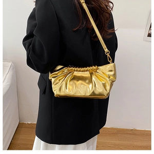 Detail of metallic gold pleated cloud clutch bag with sleek chain strap over black suit