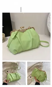 Detail of light green pleated shell bag featuring flower clasp and adjustable strap