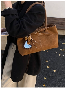 Detail of vintage brown suede tote bag featuring contrast stitching and heart leopard charm