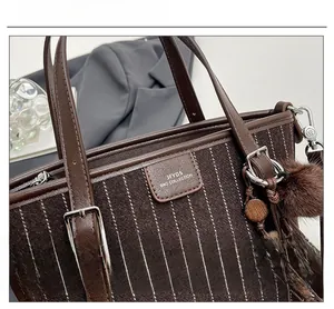 Détail d'un sac seau vintage à rayures marron avec poignées en cuir et pompon