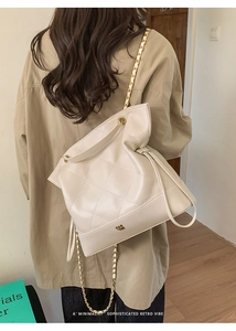 Detail of off-white quilted tote bag with gold chain strap and drawstring closure