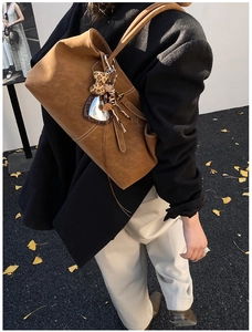 Detail of a brown leather tote bag featuring contrast stitching and a leopard print bow