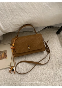 Detail of brown matte retro square bag with wooden beads and golden lock on plush rug