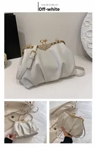 Detail view of cream white cloud bag showing rhinestone butterfly clasp and pleated texture