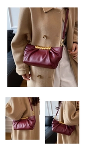 Detail of burgundy pleated cloud bag with golden spiral accent shown on model