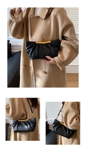 Detail of black pleated leather clutch with golden twisted handle and crossbody strap