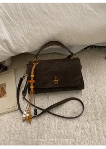 Detail of dark brown vintage faux leather handbag with wooden bead tassel and gold clasp