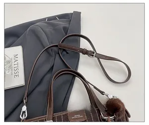 Détail de la bandoulière en cuir réglable et du tissu texturé sur le sac seau marron
