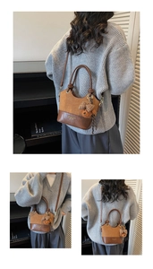 Detail of a retro color-block handbag featuring a suede texture and cute bear pendant