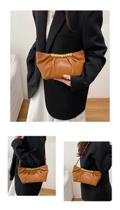 Detail view of brown pleated cloud bag featuring golden metal gathered handle and thin strap