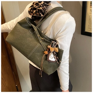 Detail of vintage olive green tote bag featuring contrast stitching and leopard bow charm