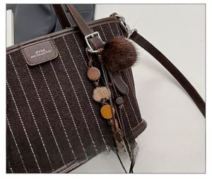 Détail d'un sac seau vintage en laine texturée avec des breloques décoratives en fourrure