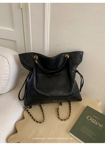 Detail of black quilted leather tote featuring gold chain and luxury metal logo