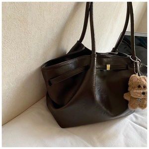 Macro detail of dark brown tote bag featuring glossy leather texture and cute puppy charm