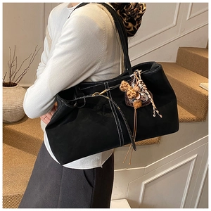 Detail of black large tote bag with white stitching and stylish leopard print bow charm