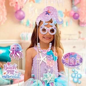 Girl using mermaid party photo booth props with glittery shells and seashell glasses