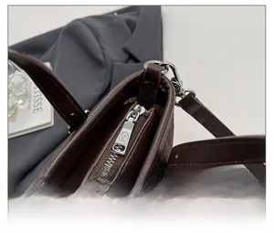 Détail de la fermeture éclair en métal et de l'anse en cuir du sac seau marron rétro