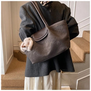 Detail of taupe suede tote bag with brown leather flap and cute plush bunny charm