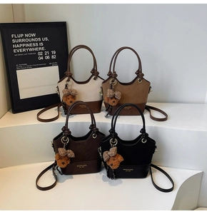 Detail of four suede tote bags in various colors with cute bear charms and bows
