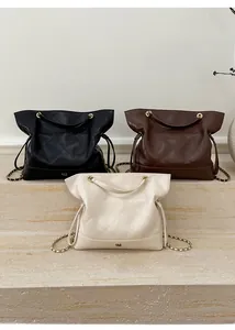Three large quilted tote bags in black, brown and cream with gold chain straps