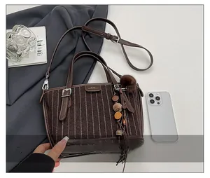 Détail du sac seau vintage avec tissu en laine texturé et pompon en perles de bois